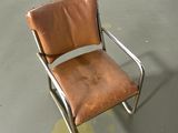 a brown leather chair that is on a cement floor