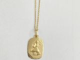 a gold necklace with an image of a woman on it