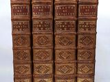 six old books are stacked on top of each other on a white surface