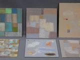 Quatre tableaux de couleurs et de formes différentes sont exposés sur une table