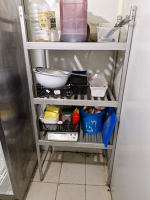 a metal shelf with pots and pans on it in a kitchen