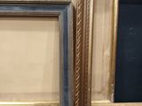two gold and blue frames on a wall with a black background