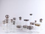 de nombreux bocaux en verre avec des couvercles argentés posés sur une surface blanche