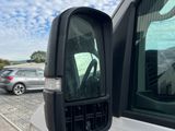 a side view mirror of a white van on the side of the road