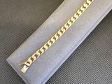 gros plan d'un bracelet en chaîne en or sur une surface grise