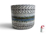 un vase blanc orné d'un motif bleu et vert