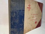 an old book with a red cross on it sitting on a white surface