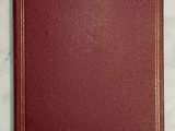 a red leather book with gold trim on a marble surface