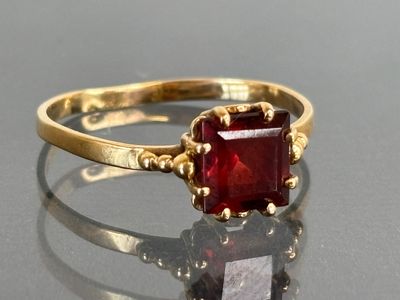 an image of a gold ring with a red stone in it
