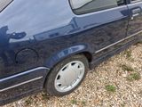 a small blue car parked in a gravel lot