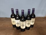 six bottles of wine are lined up on a wooden table