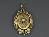 a close up of a gold pendant with a clock on it