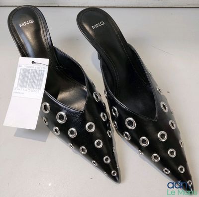 les chaussures sont noires, ornées de cercles argentés, et portent une étiquette de prix