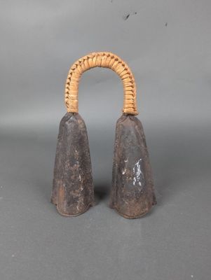 paire de cloches anciennes en bois avec une poignée en osier sur fond gris