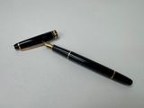 un stylo noir posé sur une table blanche, à côté d'un stylo à bille noir