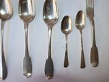 several spoons and forks are lined up on a white surface