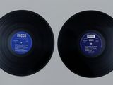 two black vinyl records sitting on top of a white surface