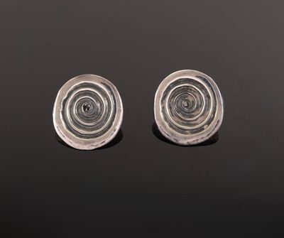 two silver earrings on a black surface with a black background
