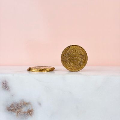 a gold coin sitting on top of a marble counter next to a pink wall