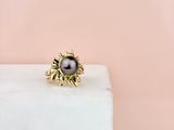 une bague ornée d'une perle noire posée sur un bloc de marbre blanc