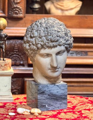 un buste d'homme posé sur une table, à côté d'un vase