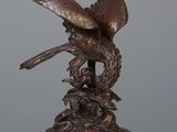 statue en bronze représentant un oiseau, posée sur un socle surmonté d'un autre oiseau