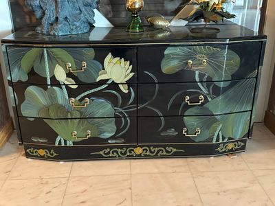 une commode noire ornée de fleurs, dans une pièce