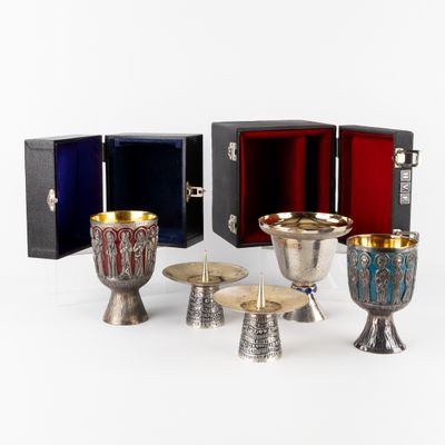 several silver and gold goblets, cups and trays on a white surface