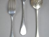 three silver spoons and a fork on a table
