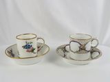 two cups and saucers with floral designs on them on a white surface