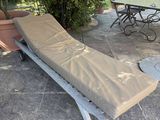 a chaise lounger on a patio with a table and chairs in the background