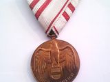 une médaille posée sur une table blanche, accompagnée d'un ruban rouge et blanc