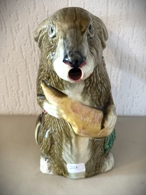 un ours en céramique qui tient une banane dans la gueule