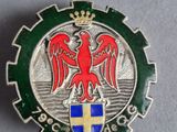 une image représentant un insigne métallique orné d'un aigle rouge
