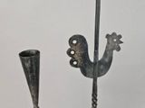 a metal object with a rooster on it next to a vase
