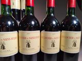 four bottles of red wine are lined up on a table