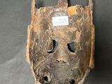 an old wooden mask with a tag on it sitting on a table