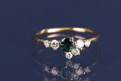 une photo d'une bague en diamant verte et blanche
