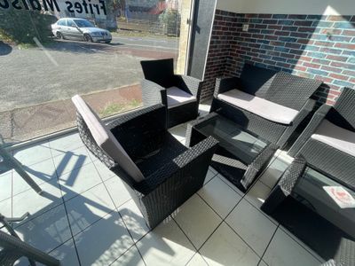 une photo d'une terrasse avec des chaises en osier et une table basse
