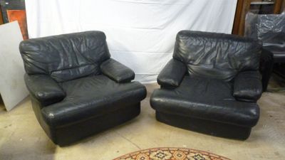 pair of black leather recliners in a room with a rug on the floor