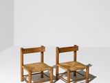 deux chaises en bois assises l'une à côté de l'autre sur une surface blanche