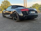the rear end of a black sports car parked in a parking lot