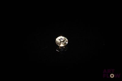 un gros plan d'un diamant posé sur une surface noire dans l'obscurité