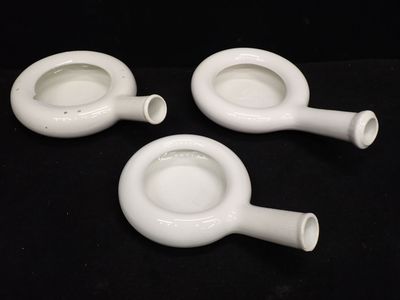 trois vases blancs posés les uns à côté des autres sur une surface noire