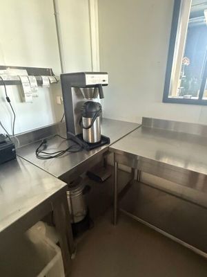 a coffee maker sitting on a stainless steel counter in a commercial kitchen