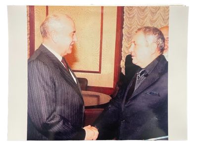 two men in suits shaking hands in a room