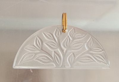 a close up of a pendant with a leaf design on it