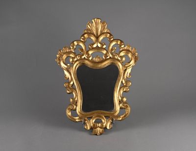 un cadre doré richement décoré surmonté d'un miroir