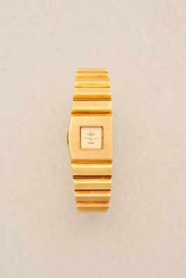 a close up of a gold wrist watch on a white surface
