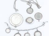 a close up of a group of silver jewelry on a white surface